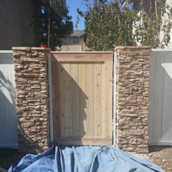 A wooden gate with stone pillars on the side.