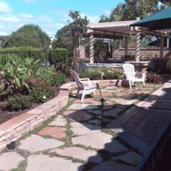 A patio with chairs and an umbrella in the background.