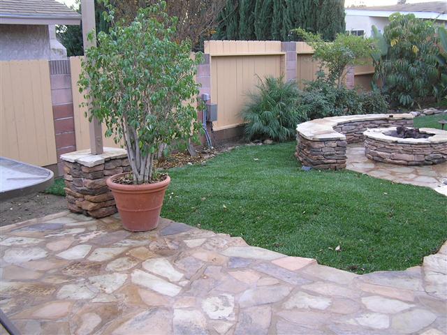 A patio with a potted plant and stone wall.