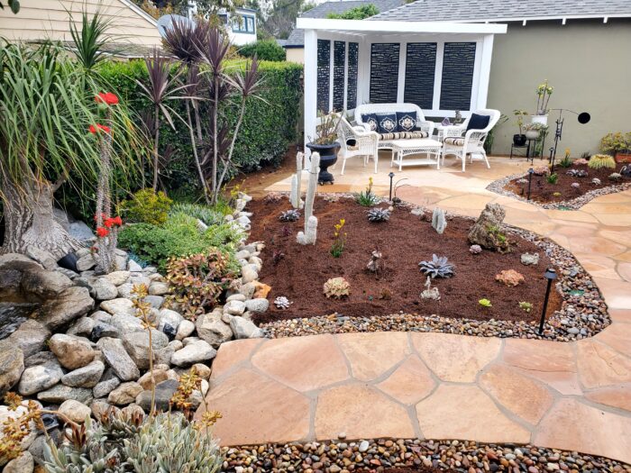 A backyard with a patio and garden furniture.